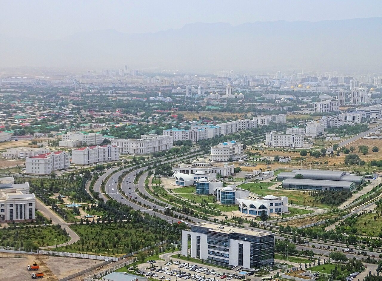 Vue aérienne d’Achgabat, ses bâtiments blancs et ses larges avenues, avec les montagnes du Kopet-Dag au loin